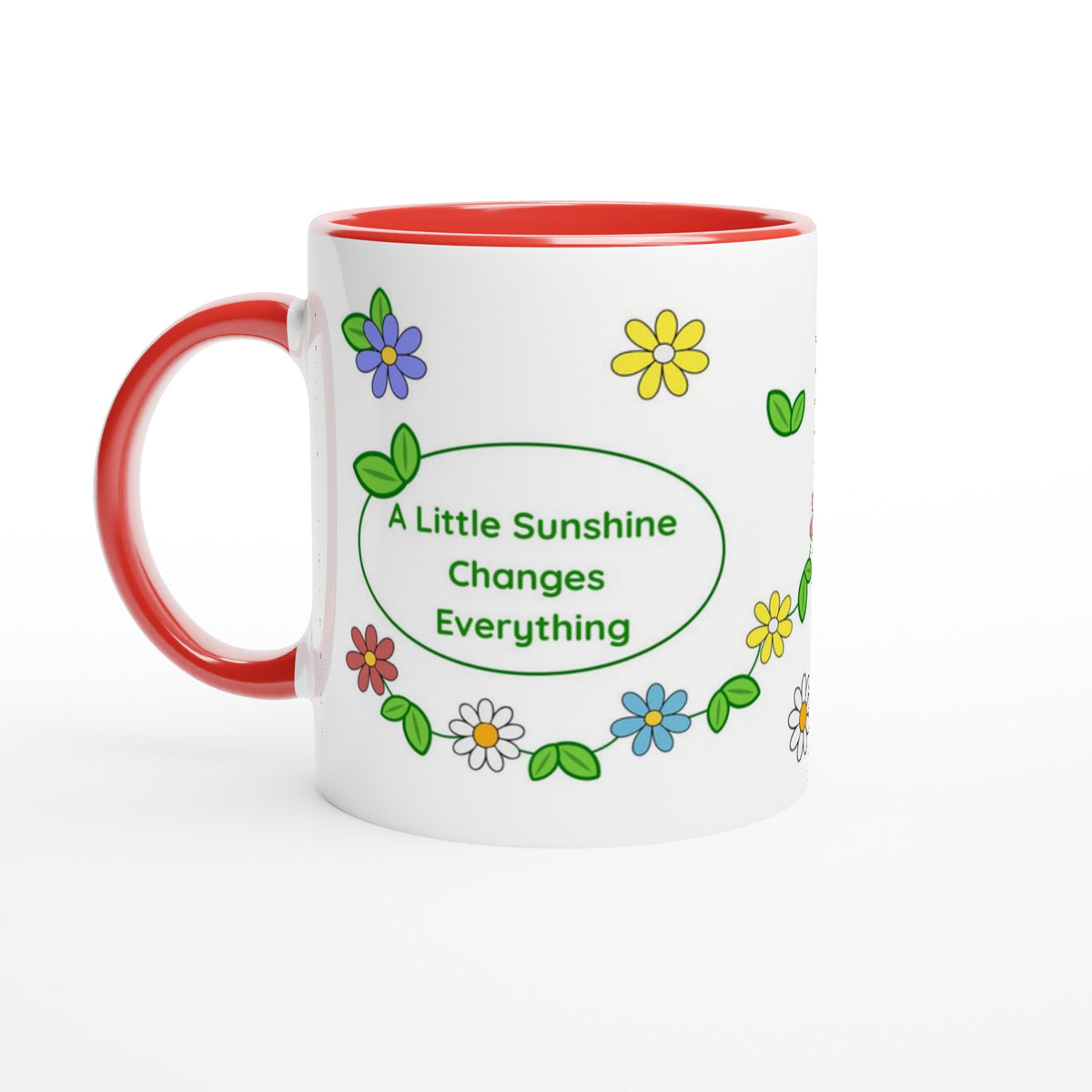 A white ceramic mug with a red handle and red interior, decorated with colorful flowers and green leaves around a green oval that reads 'A Little Sunshine Changes Everything'.
