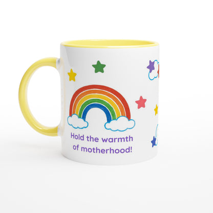 A white ceramic mug with a yellow handle and yellow interior, decorated with a colorful rainbow, stars, clouds, and the text 'Hold the warmth of motherhood!' in purple, on a white background.