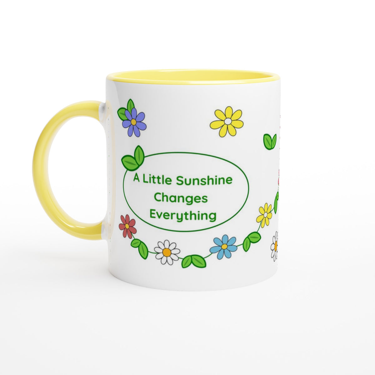 A white ceramic mug with a yellow handle and yellow interior, decorated with colorful flowers and green leaves around a central green oval that reads 'A Little Sunshine Changes Everything'.