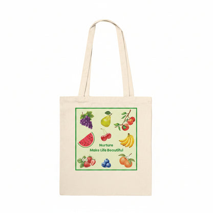 A natural beige canvas tote bag with two shoulder straps, featuring a colorful square graphic print on the front. The graphic shows various fruits (grapes, pear, cherries, watermelon, bananas, blueberries, oranges) with the text 'Nurture Make Life Beautiful' in green.