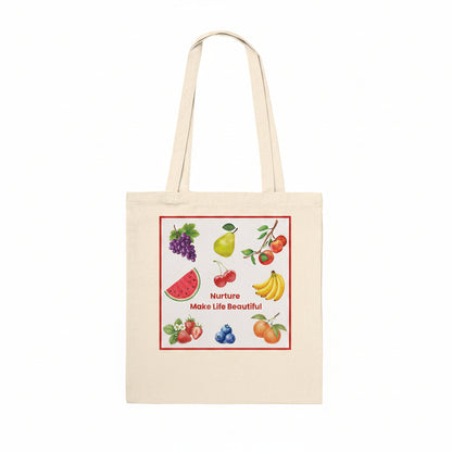 A natural canvas tote bag with dual shoulder straps, featuring a colorful fruit illustration and the text 'Nurture Make Life Beautiful' printed on the front, set against a plain white background.