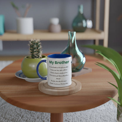 A white ceramic mug with a blue handle and rim sits on a round wooden coaster on a light wood table. The mug is printed with the text 'My Brother' 