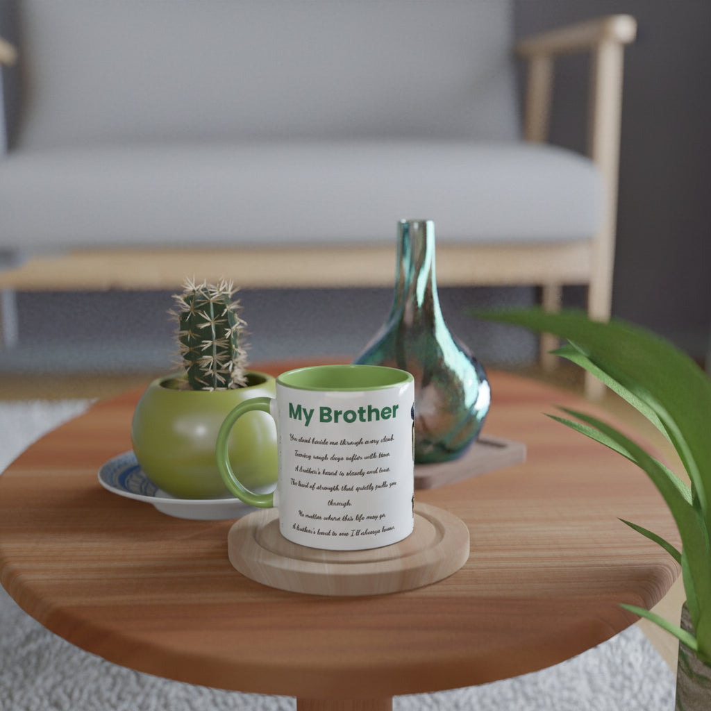 A white ceramic mug with a green interior and handle, printed with the text 'My Brother', sits on a wooden coaster on a round wooden table. 