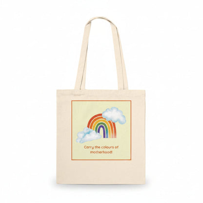 A natural canvas tote bag with a printed graphic of a rainbow, clouds, and the text 'Carry the colours of motherhood!' on a clean white background.