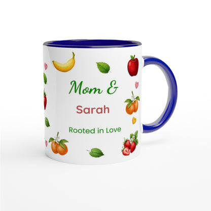 A white ceramic mug with a dark blue interior, handle, and rim, decorated with illustrations of fruits and the personalized text 'Mom & Sarah Rooted in Love'.