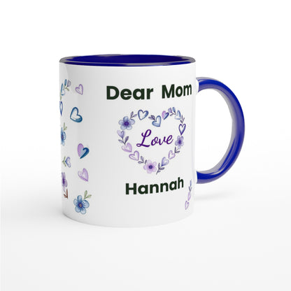 A white ceramic mug with a dark blue interior, handle, and rim, printed with 'Dear Mom Hannah' and a purple floral heart design on the front, set against a plain white background.