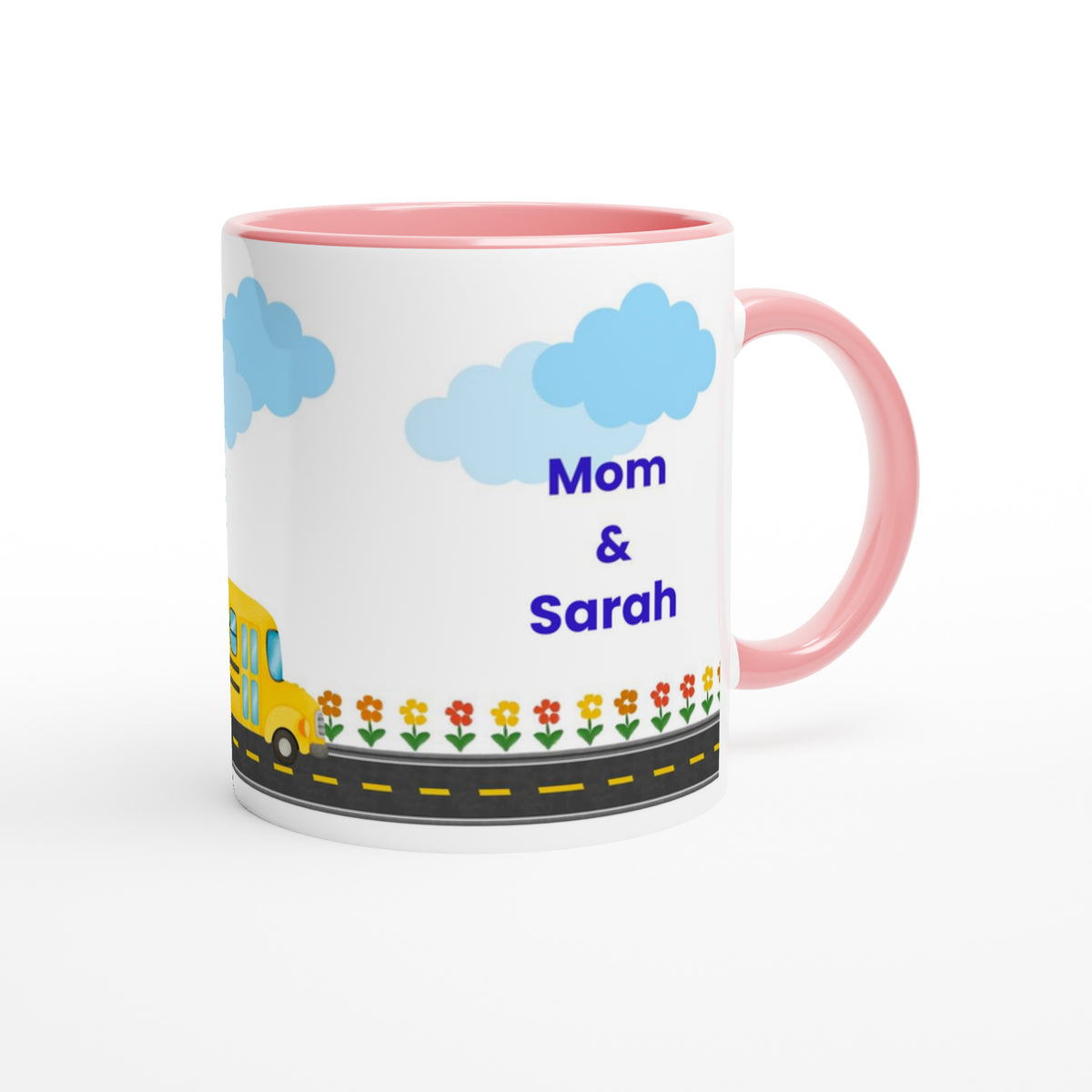 A white ceramic mug with a pink handle and interior, decorated with a cartoon school bus, flowers, a road, and the text 'Mom & Sarah' in blue, shown on a white background.