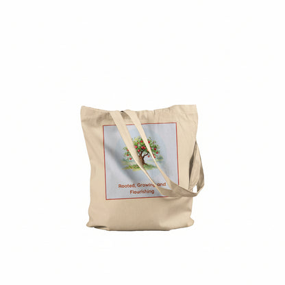A beige canvas tote bag with two shoulder straps, featuring a printed graphic of a tree with the text 'Rooted, Growing and Flourishing' on the front, set against a plain white background.