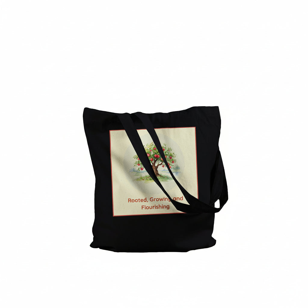 A black canvas tote bag with two shoulder straps, featuring a square graphic print on the front. The print has a cream background with a colorful tree illustration and the text 'Rooted, Grown and Flourishing' in red.