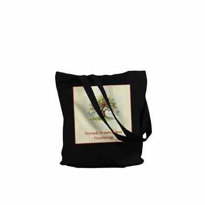 A black canvas tote bag with two shoulder straps, featuring a square graphic print on the front. The print has a cream background with a colorful tree illustration and the text 'Rooted, Grown and Flourishing' in red.