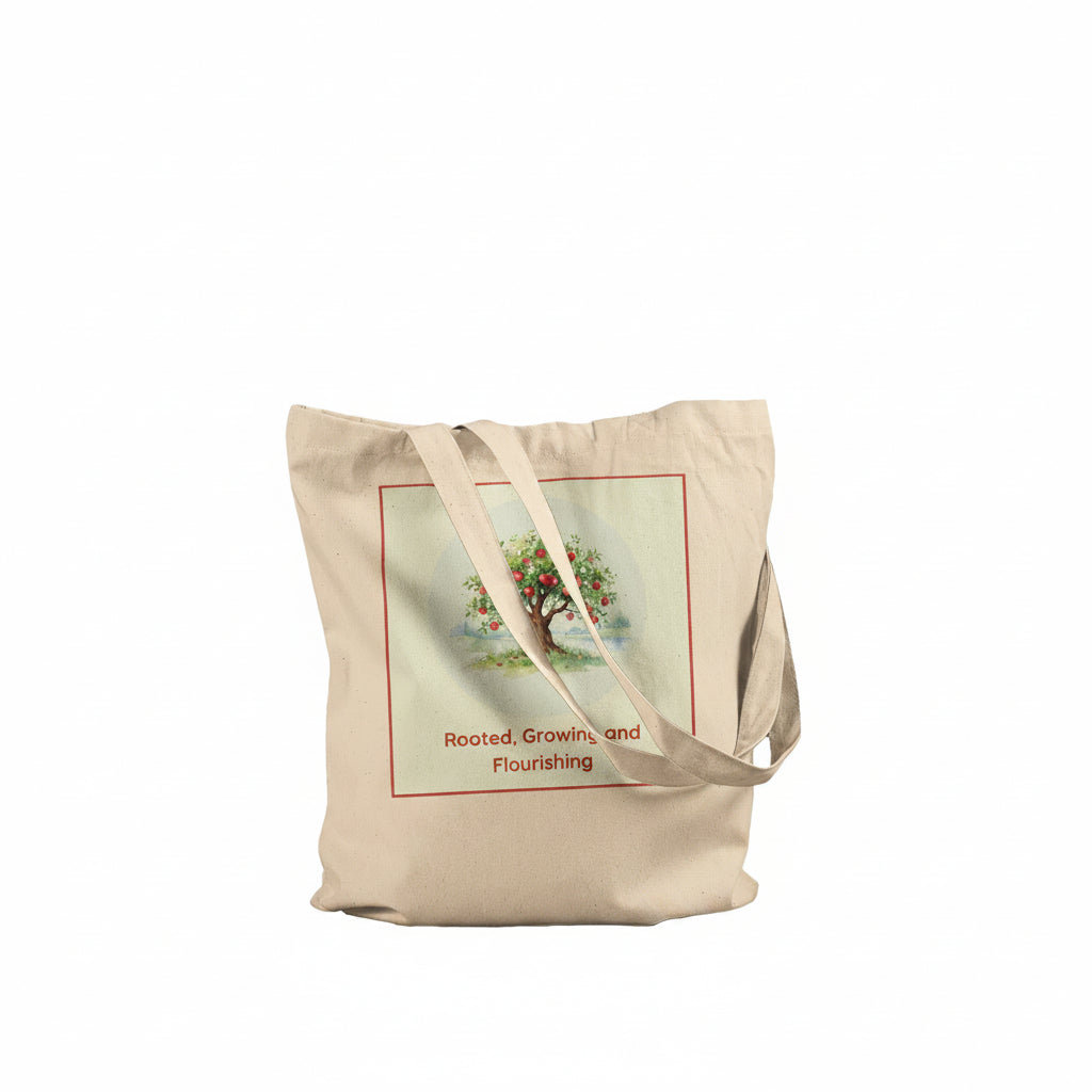 A beige canvas tote bag with two shoulder straps, featuring a vintage-style illustration of an apple tree with the text 'Rooted, Growing, and Flourishing' printed on the front.