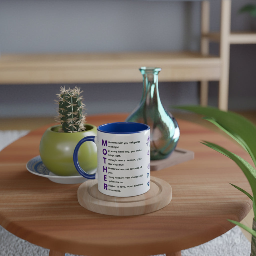 A white ceramic mug with a blue interior and handle sits on a wooden coaster on a round wooden table. The mug features a blue and black typographic design spelling 'MOTHER' with a quote.