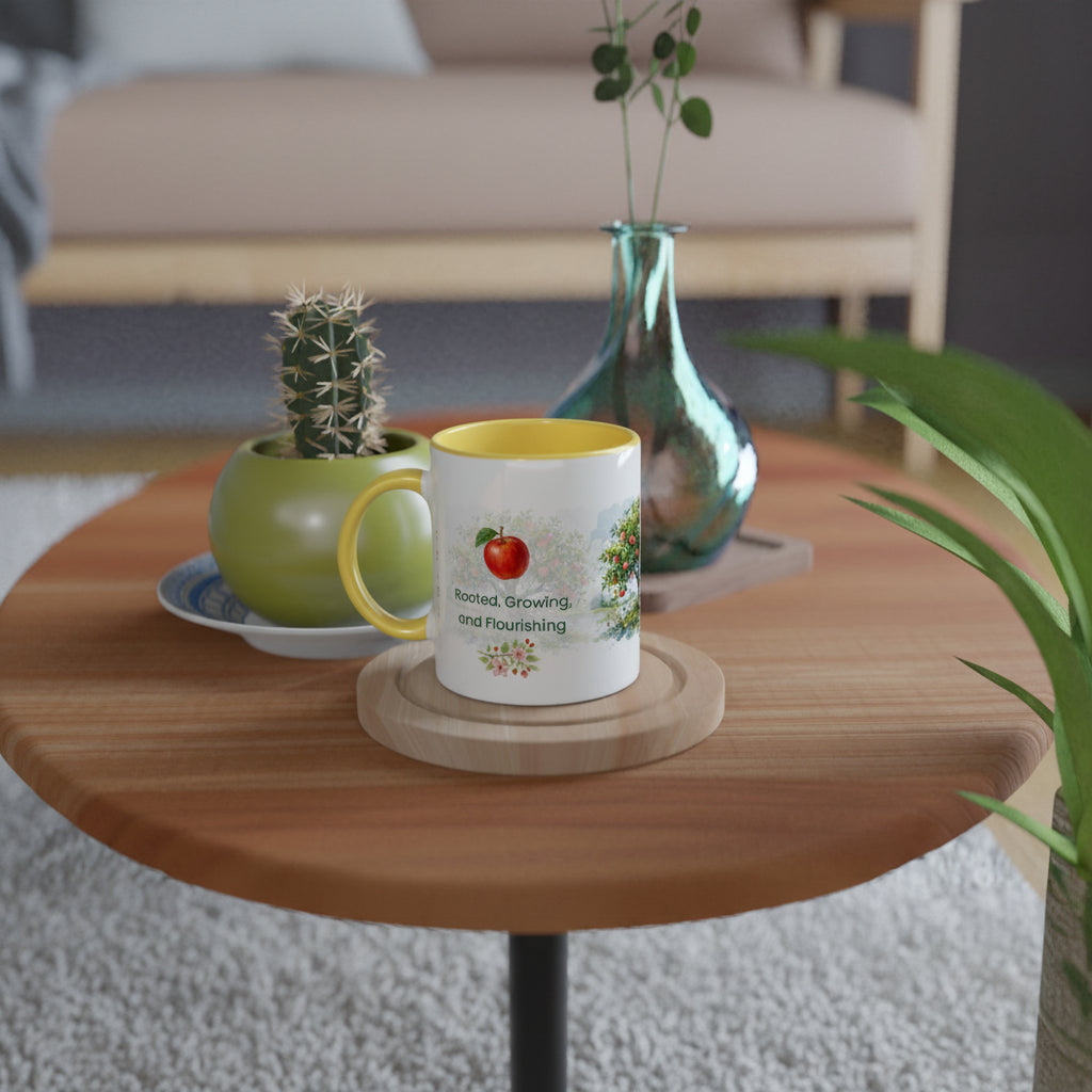 A white ceramic coffee mug with a yellow interior and handle, featuring a red apple 