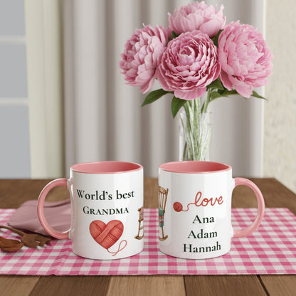 Two personalized ceramic mugs with pink interiors and handles, displayed on a table runner. One mug reads 'World's best GRANDMA' 