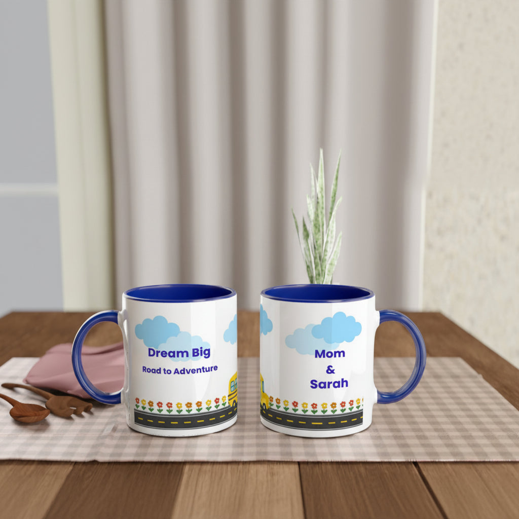 Two personalized ceramic mugs with blue interiors and handles, displayed side by side on a table runner. One mug shows the front with the text 'Dream Big Road to Adventure' and a small illustration, while the other shows the back with 'Mom & Sarah' and a matching illustration.
