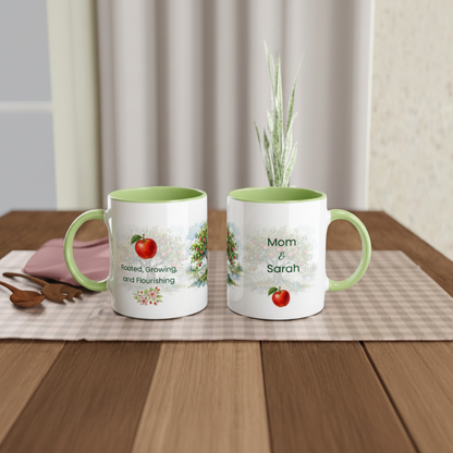 Two personalized ceramic mugs with mint green interiors and handles sit on a checkered placemat on a wooden table. 
