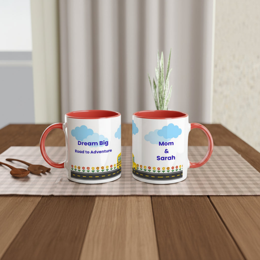 Two personalized ceramic mugs with red interiors and handles, displayed side by side on a wooden table. One mug shows a blue cloud graphic with the text 'Dream Big Road to Adventure' and the other shows 'Mom & Sarah' above a matching cloud and floral border.
