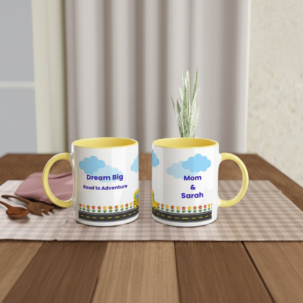 Two white ceramic mugs with yellow interiors and handles are displayed on a wooden table. One mug shows the text 'Dream Big Road to Adventure' with a yellow car and blue clouds, and the other shows 'Mom & Sarah' in the same style.