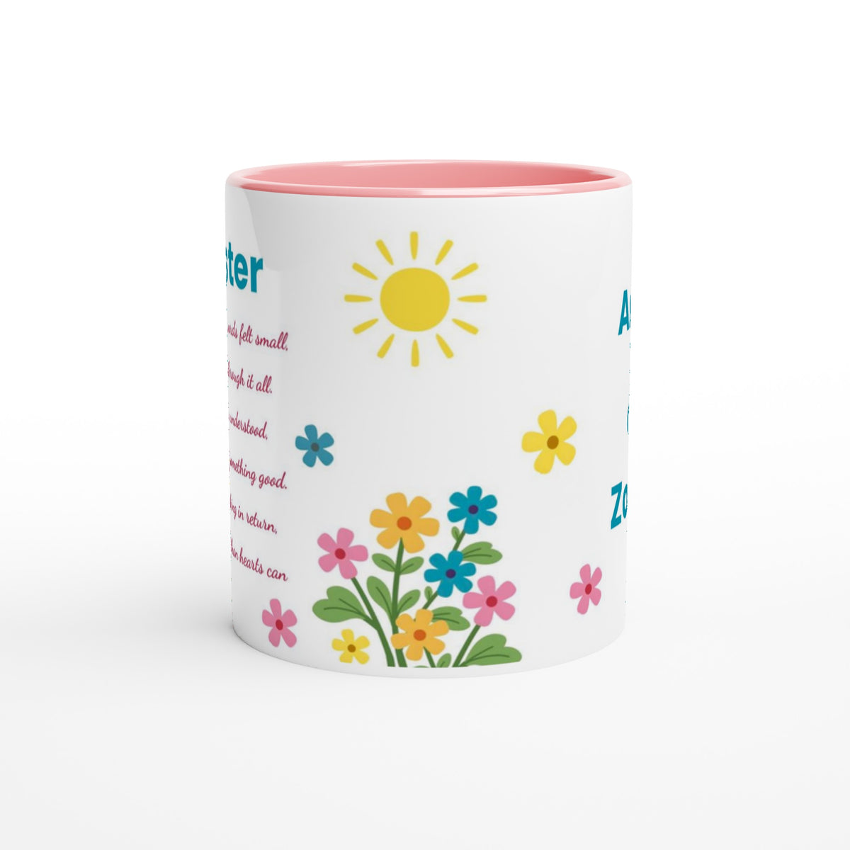 A white ceramic mug with a pink interior and rim, decorated with a colorful spring-themed print featuring a yellow sun, blue and pink flowers, and green leaves, alongside partial teal text.