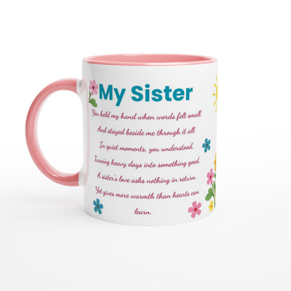 A white ceramic mug with a pink handle and pink interior, featuring the text 'My Sister' in blue and a sentimental poem below in pink, decorated with small colorful flowers.