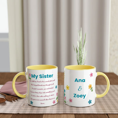 Two personalized ceramic mugs with yellow interiors and handles, displayed side by side on a wooden table. One mug is printed with a poem for 'My Sister' in pink text with small floral accents, and the other is printed with 'Ana & Zoey' in blue text with matching floral details.