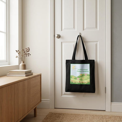 A black tote bag , hanging by the door, with a flowers and meadow graphic on the front.