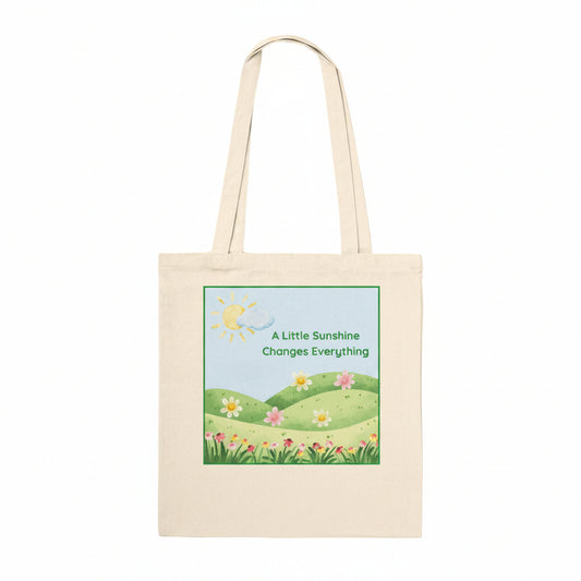 A natural coloured tote bag, with a flowers and meadow graphic and quote "A little sunshine changes everything".