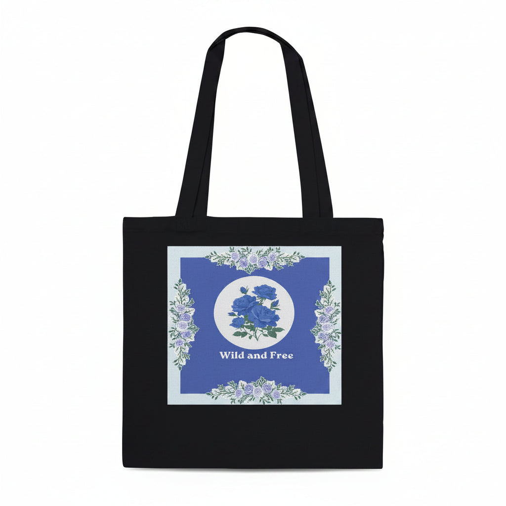A black canvas tote bag with long handles, featuring a square graphic print on the front. The print has a blue background with a central white circle containing blue roses, surrounded by a border of light blue and white flowers, and the words 'Wild and Free' printed below.