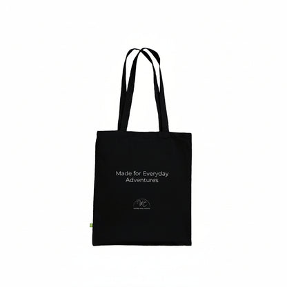 A black canvas tote bag with white printed text reading 'Made for Everyday Adventures' and a small circular logo near the bottom, shown on a plain white background.