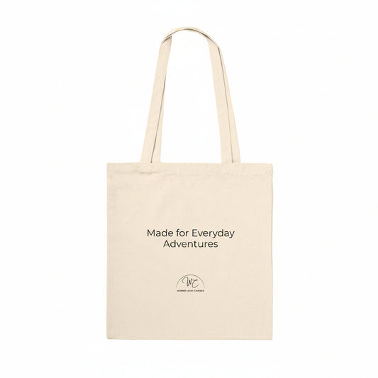 A natural canvas tote bag with black printed text reading 'Made for Everyday Adventures' and a small circular logo near the bottom, shown on a plain white background.