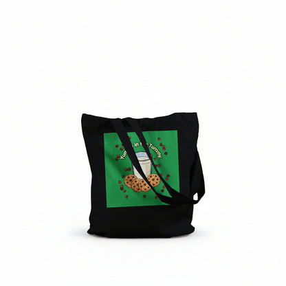 A black canvas tote bag with two shoulder straps, featuring a green square graphic on the front with a milk glass and cookies