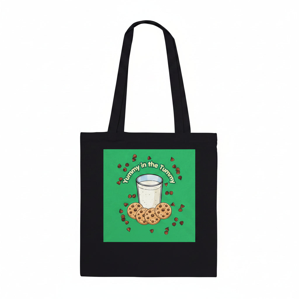 A black canvas tote bag with two shoulder straps, featuring a square green graphic print on the front. The graphic shows a white glass of milk surrounded by chocolate chip cookies and small red hearts, with the text 'Tummy in the Tummy' arched above them.